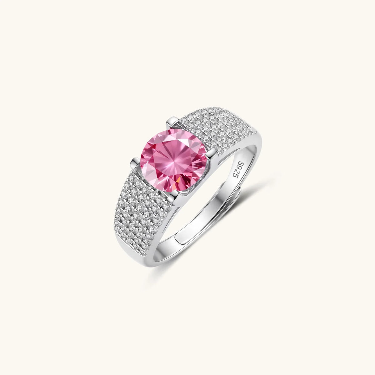 Adjustable sterling silver ring with round pink moissanite center stone and pavé crystal detailing on cream background.