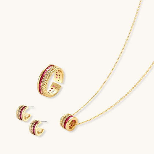 Three-piece jewelry set featuring 14K gold plated pieces with deep red cubic zirconia stones and clear crystals on cream background.
