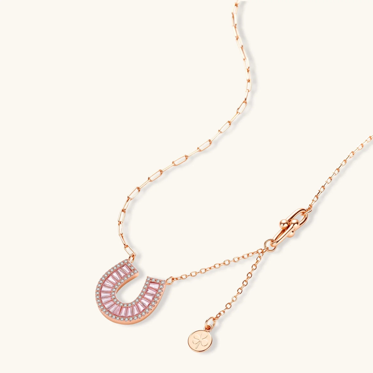 Rose gold-plated horseshoe pendant necklace and matching stud earrings set with pink baguette zirconia stones.