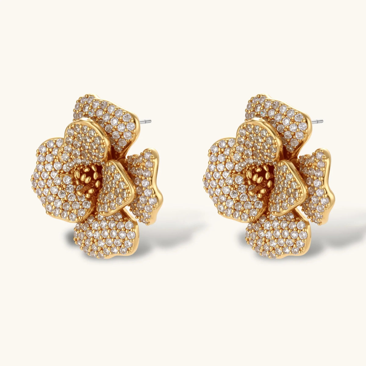 Gold plated flower pendant necklace with white beads and matching cubic zirconia flower stud earrings on a cream background.
