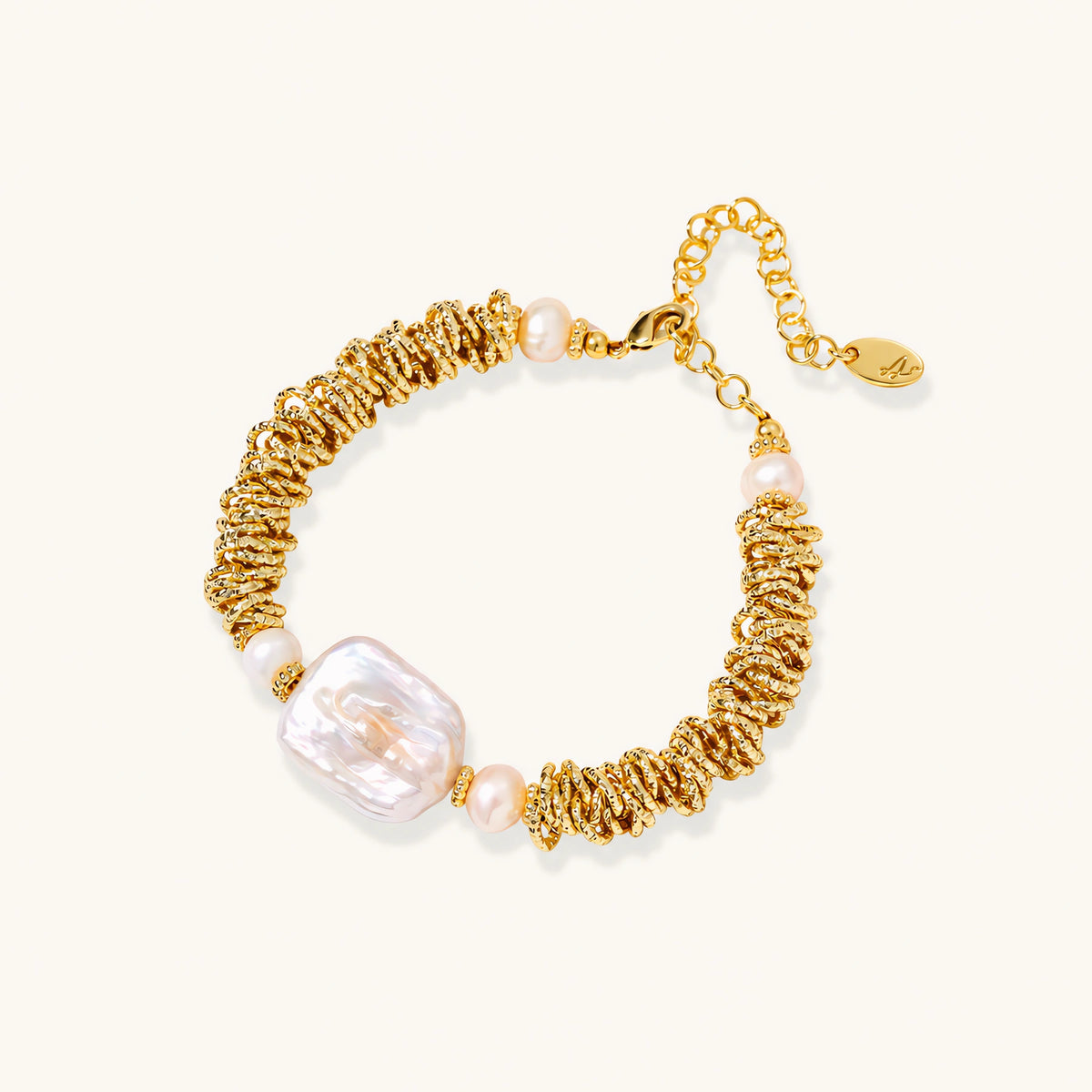 18k gold-plated bracelet with textured wave segments, baroque pearl centerpiece, and round freshwater pearls on cream background