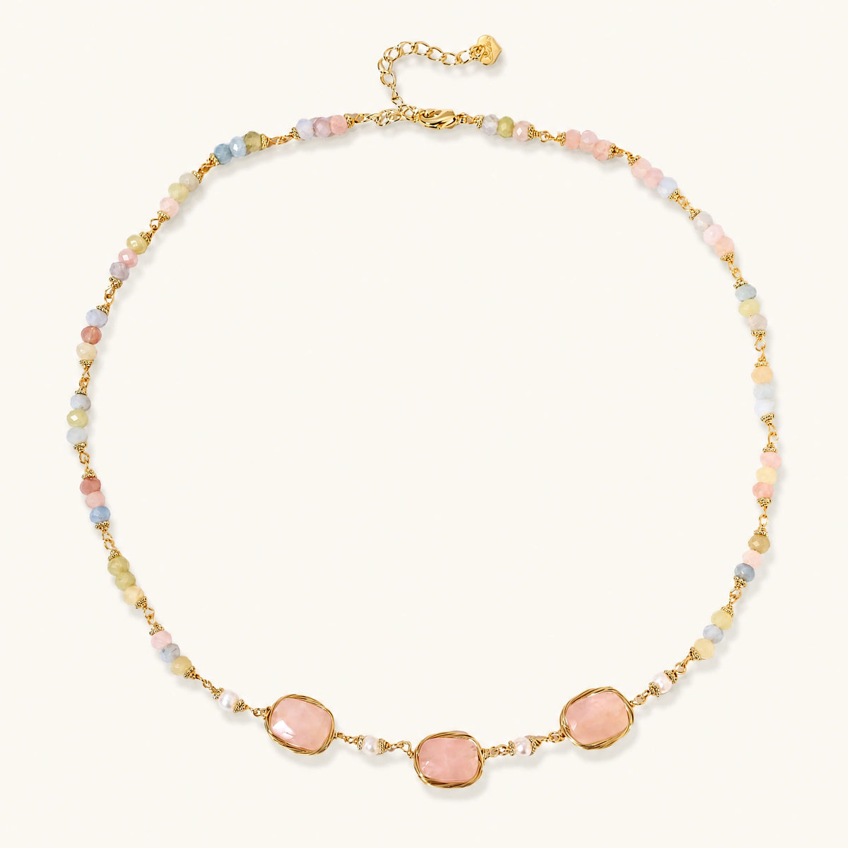 Gold necklace with three rose quartz stones, multicolor pastel beads, and pearl accents on white background.