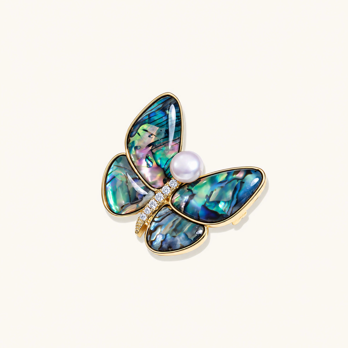 Gold-plated butterfly brooch with iridescent abalone shell wings and freshwater pearl accent on cream background.