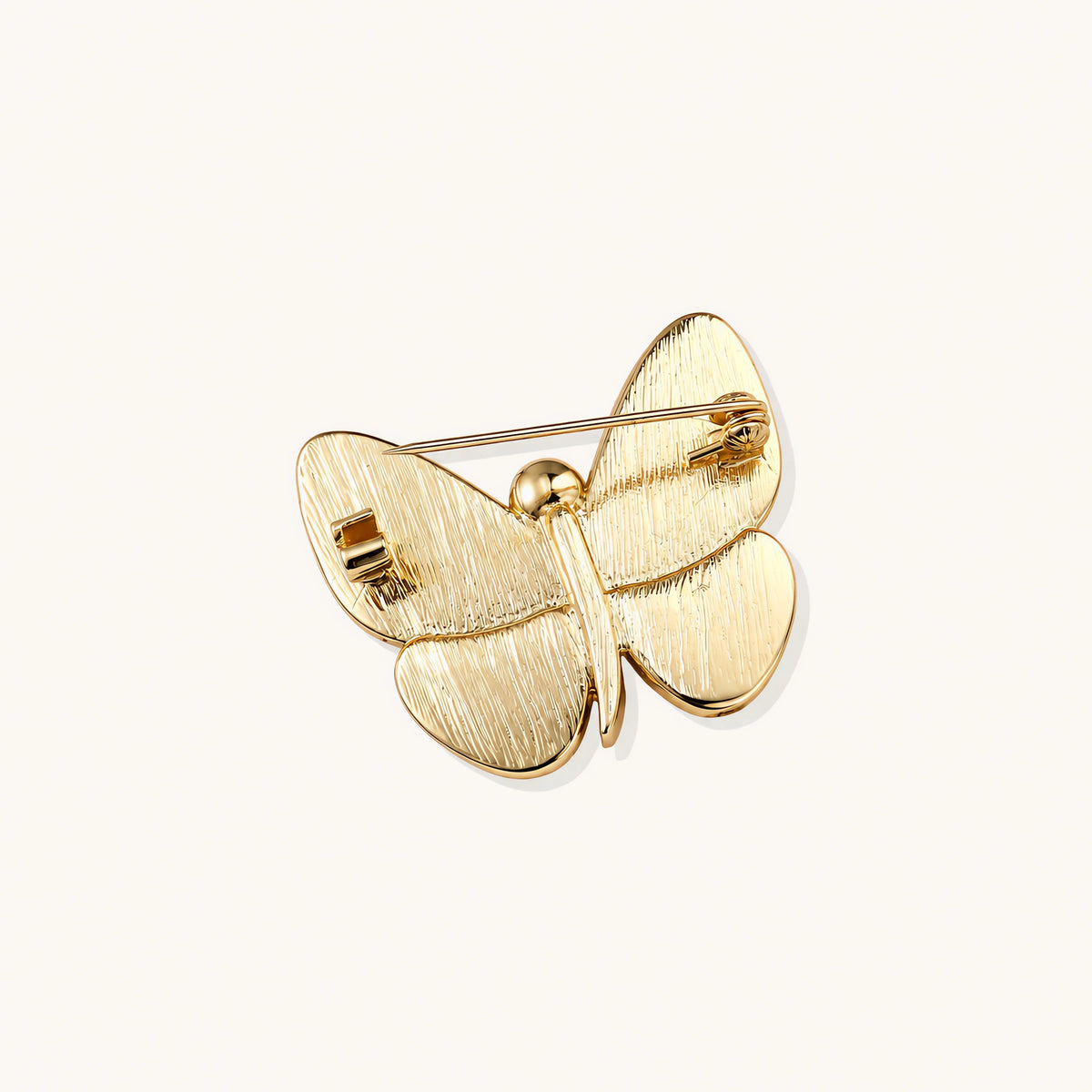 Gold-plated butterfly brooch with iridescent abalone shell wings and freshwater pearl accent on cream background.