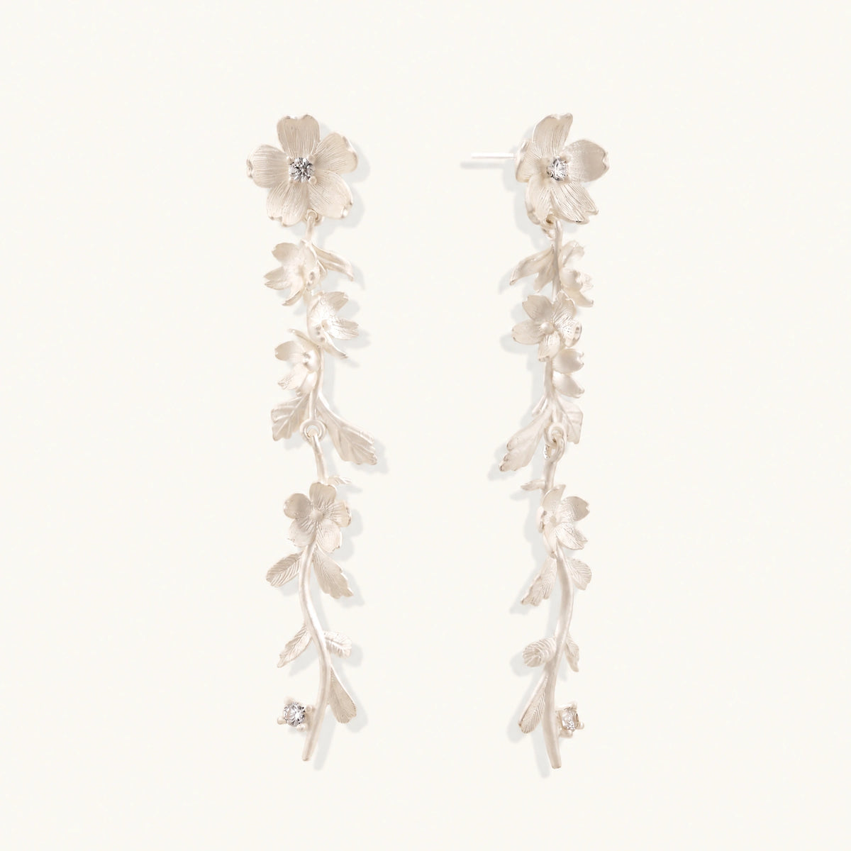 Long sterling silver drop earrings with delicate floral vine design and crystal accents on white background