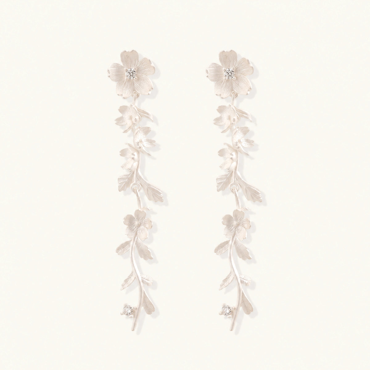 Long sterling silver drop earrings with delicate floral vine design and crystal accents on white background