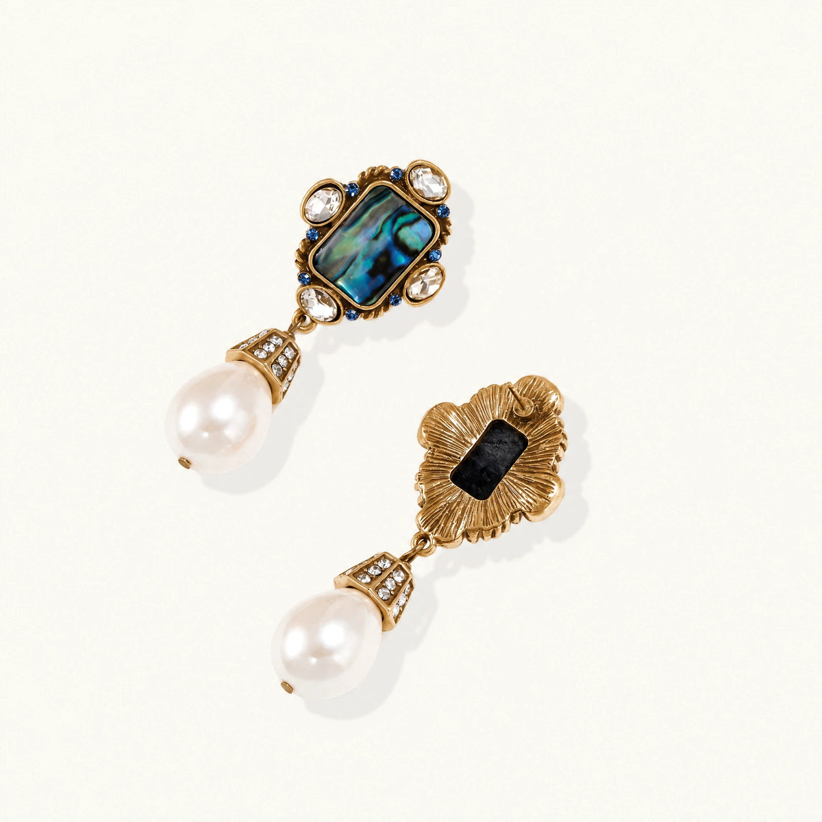 Pair of vintage-style gold plated drop earrings with iridescent abalone shell panels, clear and blue crystals, and white teardrop beads.
