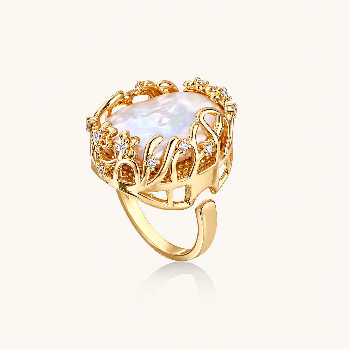 Gold filigree crown ring cradling an iridescent baroque freshwater pearl with crystal accents on white background