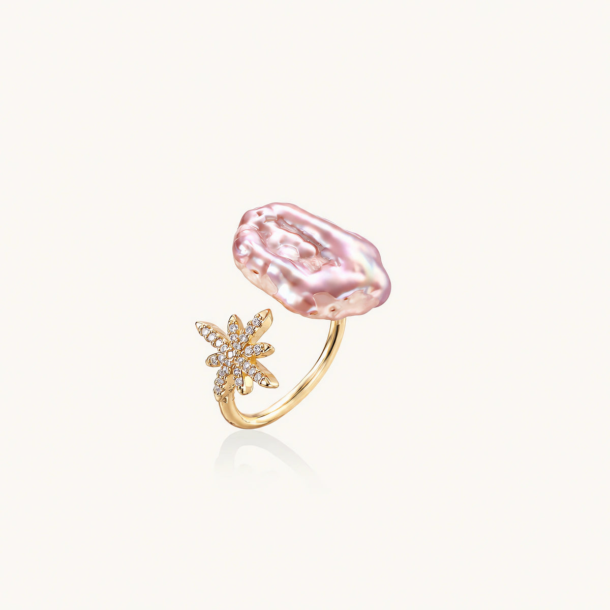 Adjustable gold ring with pink baroque freshwater pearl and crystal-studded star charm on white background