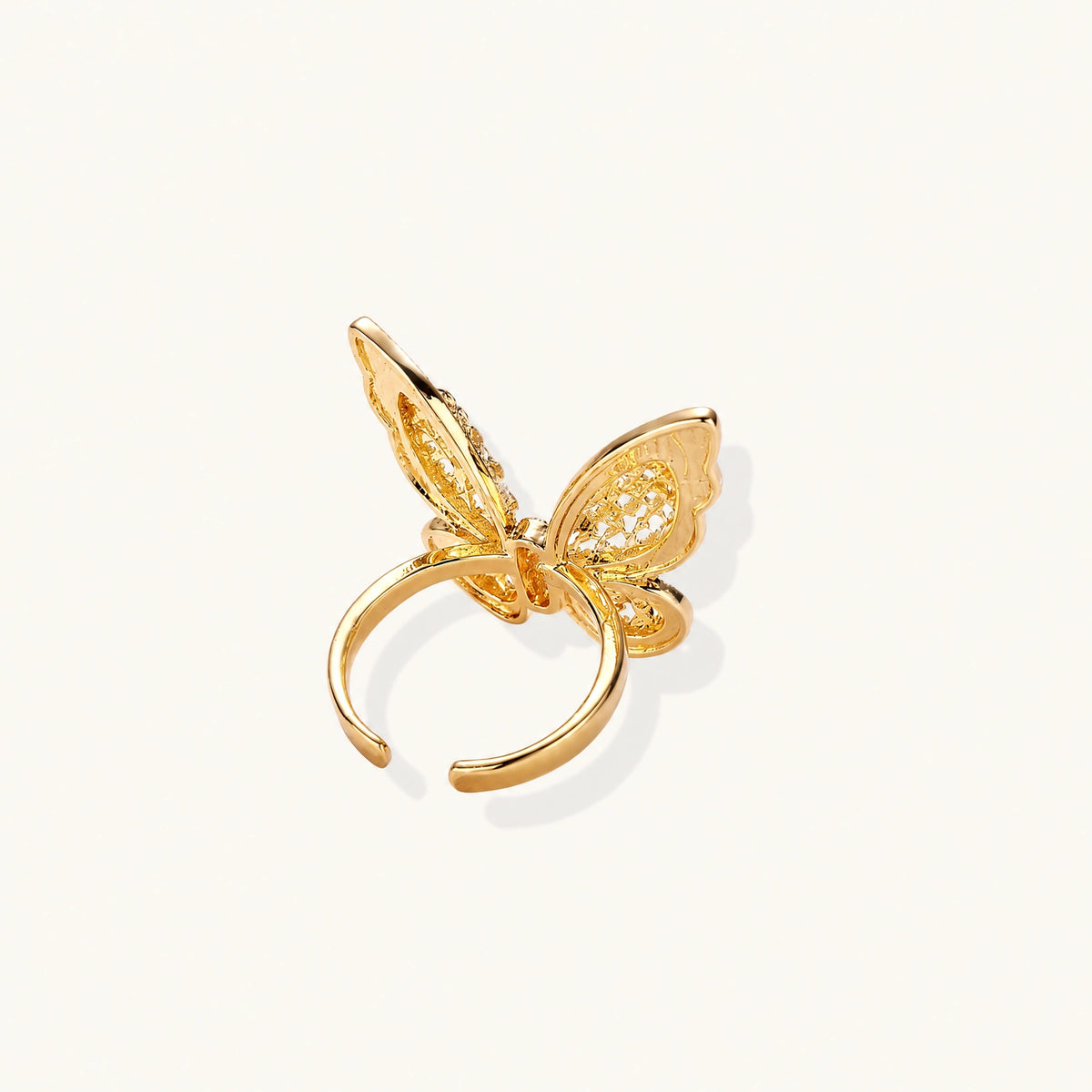 Intricate gold-plated butterfly ring with filigree cutout wings and adjustable band on white background.