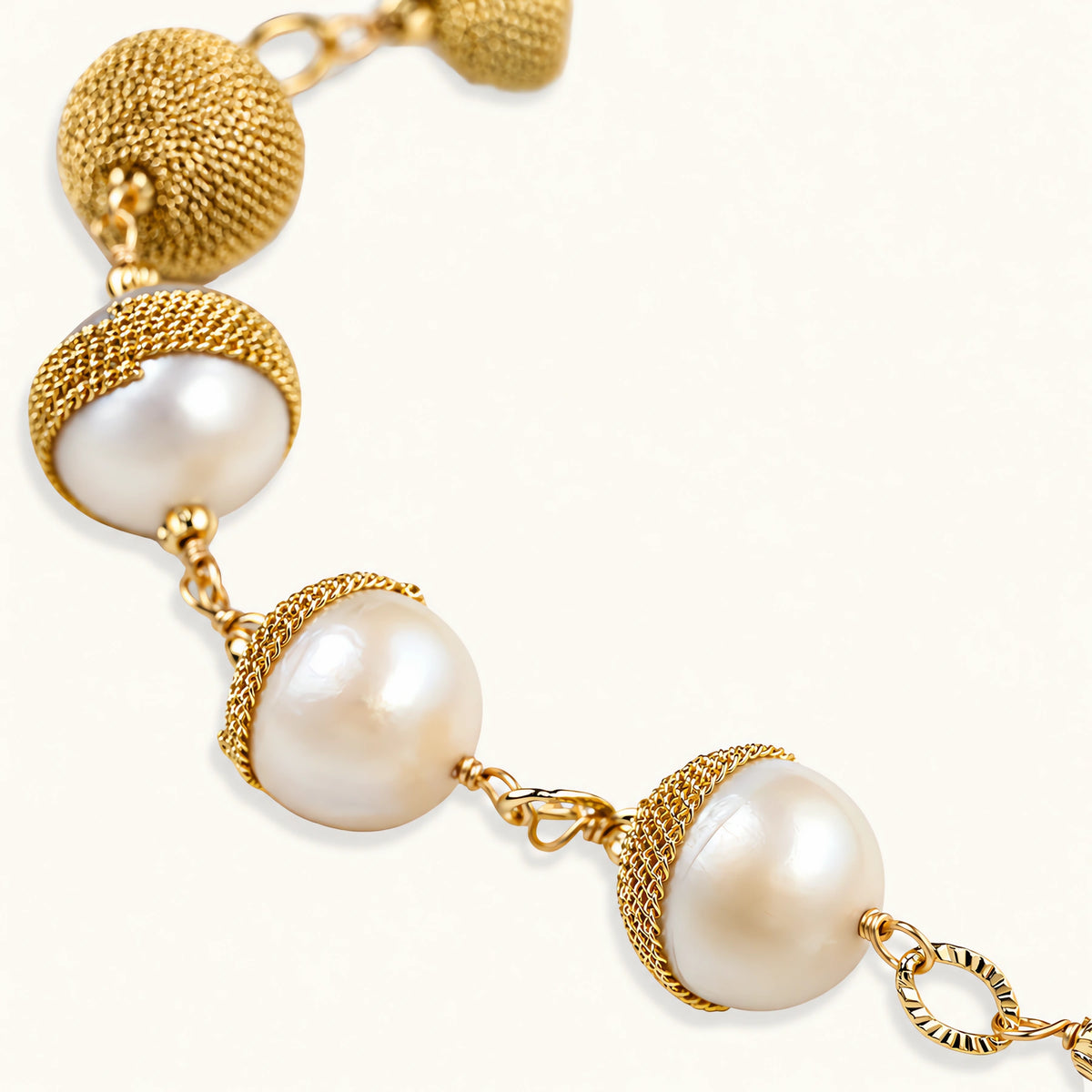 Adjustable bracelet with baroque pearls wrapped in delicate gold mesh netting connected by textured chain links