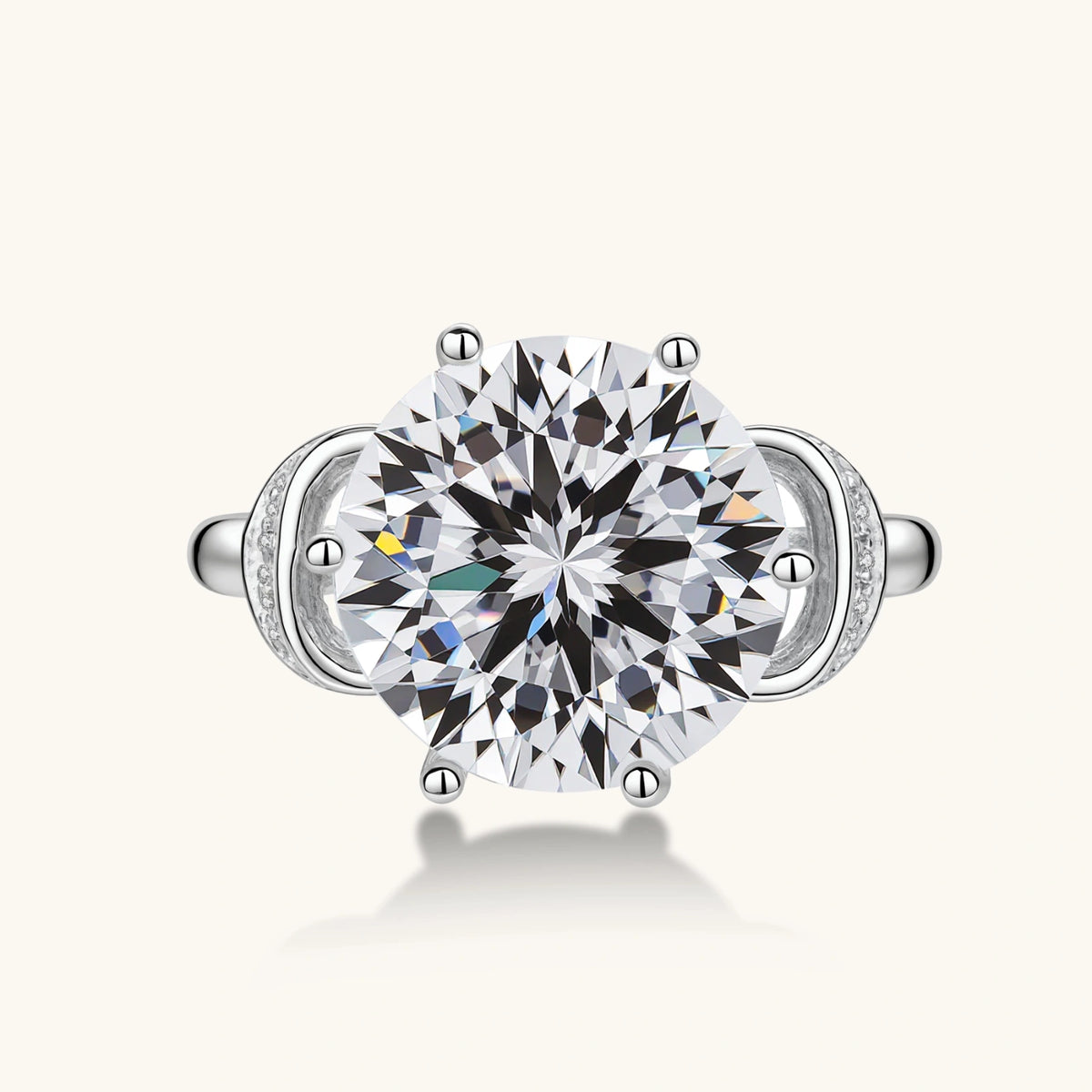 Sterling silver ring with 5ct round moissanite center stone and intricate bow design with pavé accents on white background.